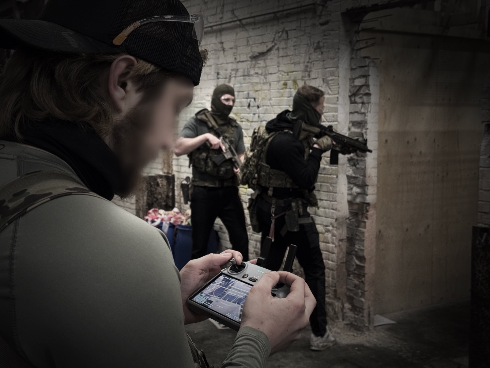 Operator mit Drohnensteuerung, im Hintergrund sichern Operators einen Bereich